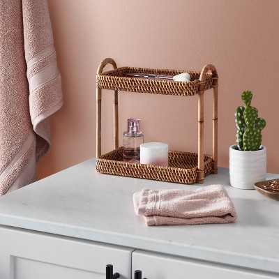 Two-tier woven organizer holding bathroom essentials on a vanity counter